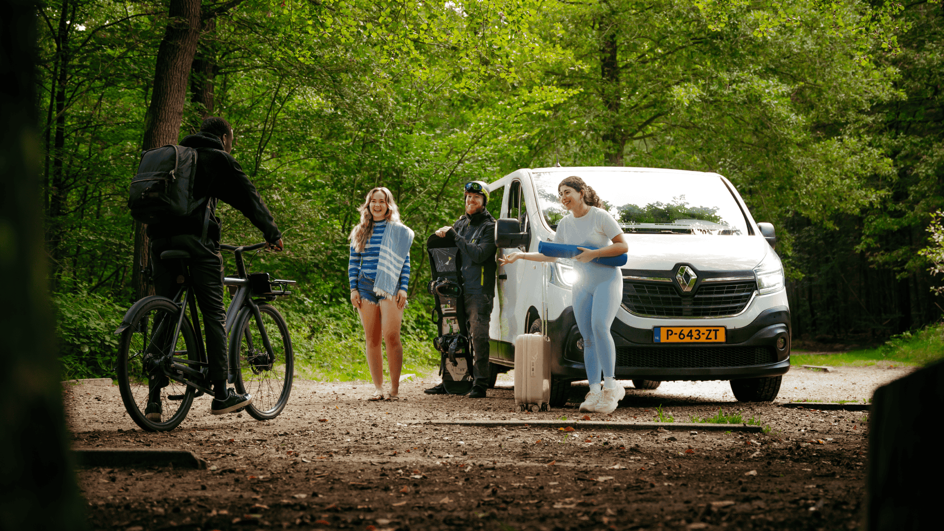 Groep mensen met fietsen en een bus in het bos tijdens een shoot, beeld bij een aftermovie laten maken