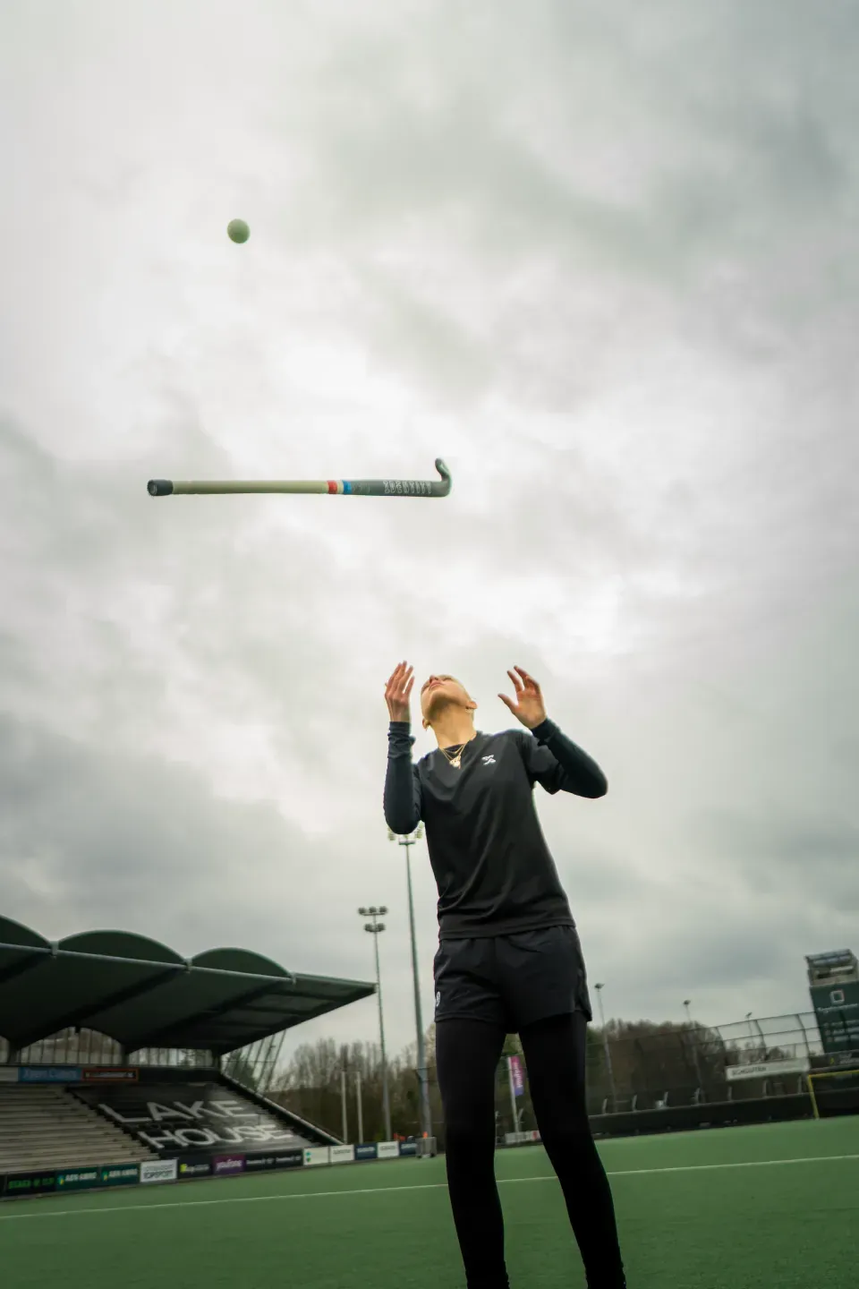 Hockeyster in X-Skills shirt kijkt omhoog naar haar stick en de bal boven het veld