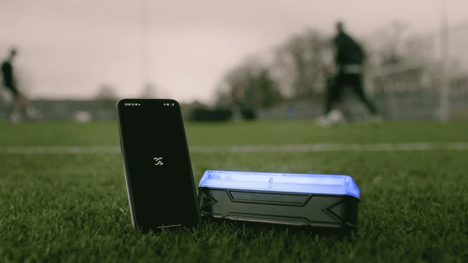 Smartphone met het X-Skills logo naast een beam met blauwe leds in het gras
